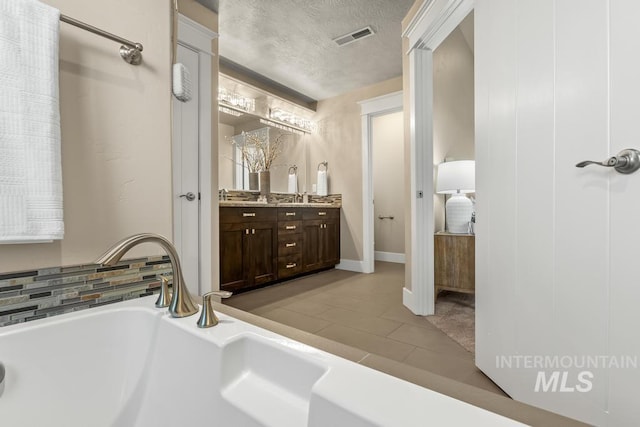 bathroom featuring tile patterned flooring, vanity, a bathtub, and a textured ceiling