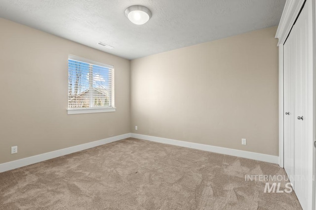 unfurnished bedroom with a textured ceiling, light colored carpet, and a closet