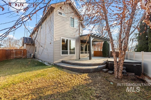 back of property with a patio area, a yard, and a hot tub