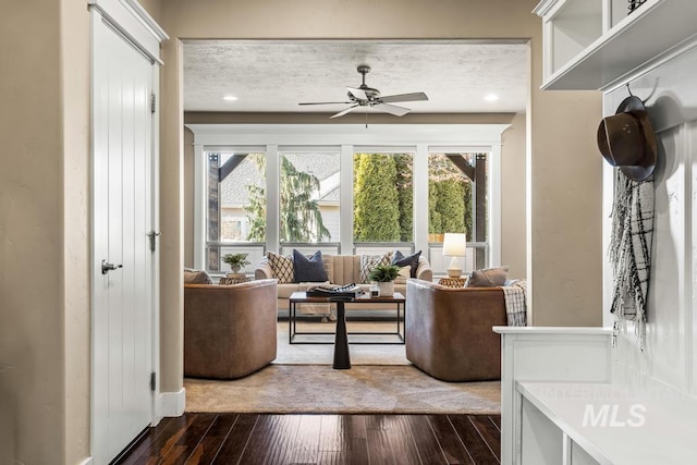 living room with ceiling fan, dark hardwood / wood-style flooring, and a textured ceiling