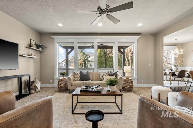 carpeted living room featuring a textured ceiling and ceiling fan with notable chandelier