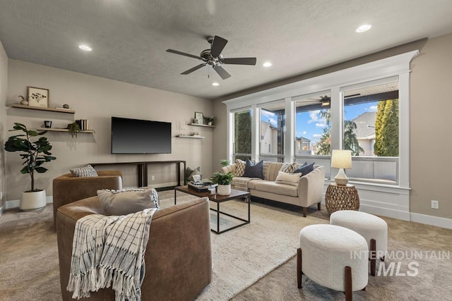 living room featuring ceiling fan, light colored carpet, and a textured ceiling