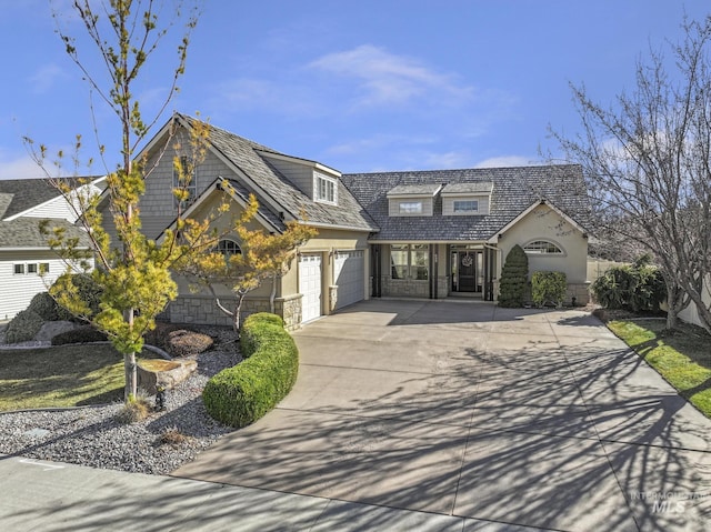 view of front of house featuring a garage, stone siding, driveway, and stucco siding