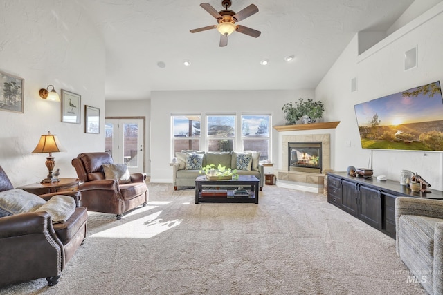 carpeted living area featuring a tiled fireplace, baseboards, visible vents, and a ceiling fan