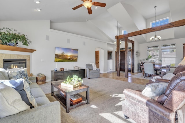 living room with visible vents, ceiling fan with notable chandelier, a tile fireplace, arched walkways, and high vaulted ceiling