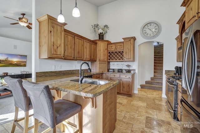 kitchen featuring a kitchen bar, a sink, a peninsula, appliances with stainless steel finishes, and a towering ceiling