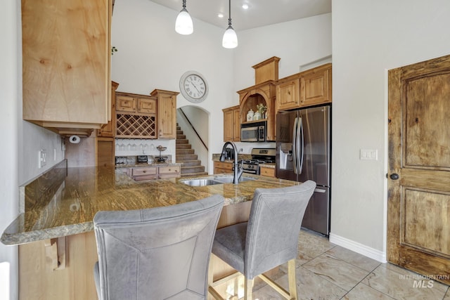 kitchen featuring a sink, appliances with stainless steel finishes, a kitchen breakfast bar, arched walkways, and open shelves