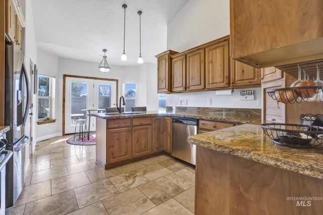 kitchen featuring brown cabinets, a sink, decorative light fixtures, appliances with stainless steel finishes, and a peninsula