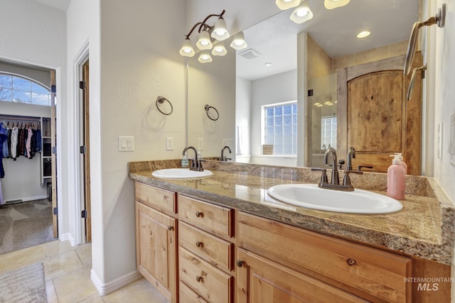 full bath with a walk in closet, double vanity, visible vents, and a sink