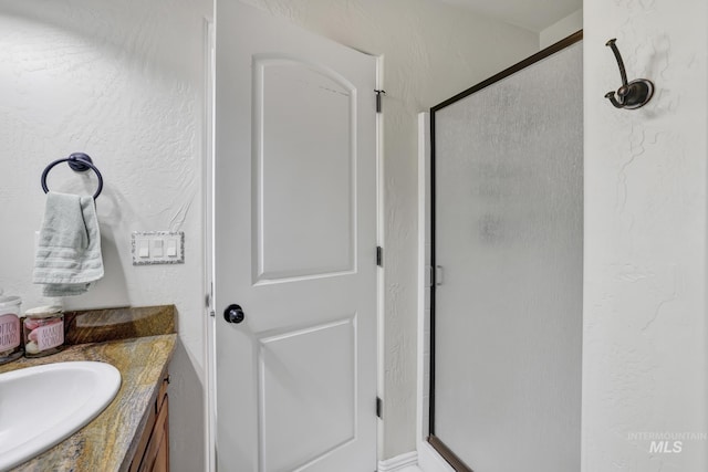 full bath featuring a stall shower, vanity, and a textured wall