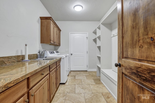 laundry area with baseboards, cabinet space, a sink, a textured ceiling, and washer and dryer