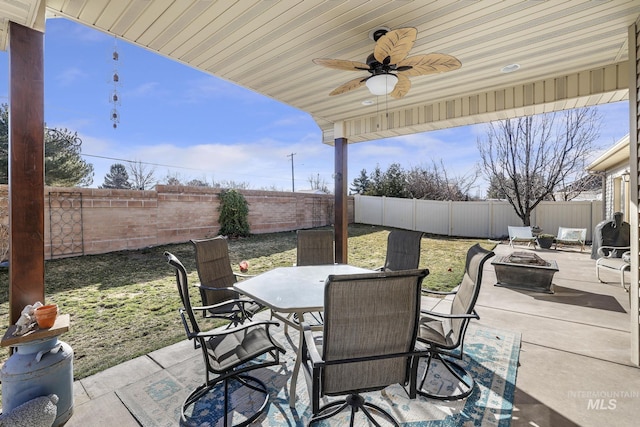 view of patio with an outdoor fire pit, outdoor dining area, a fenced backyard, and a ceiling fan