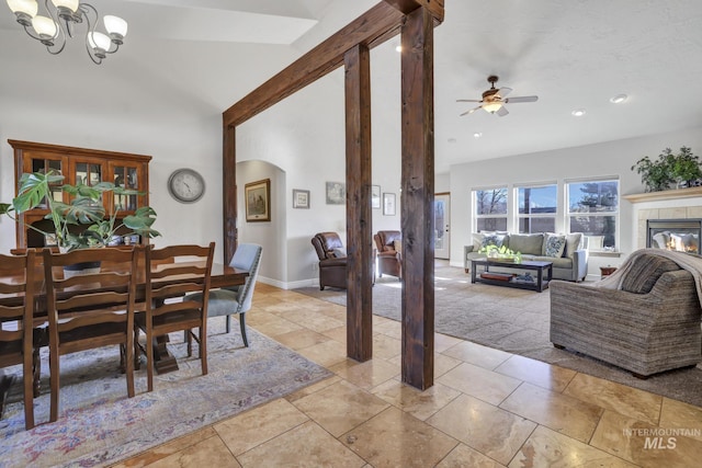 dining room with baseboards, arched walkways, a tile fireplace, vaulted ceiling, and light carpet