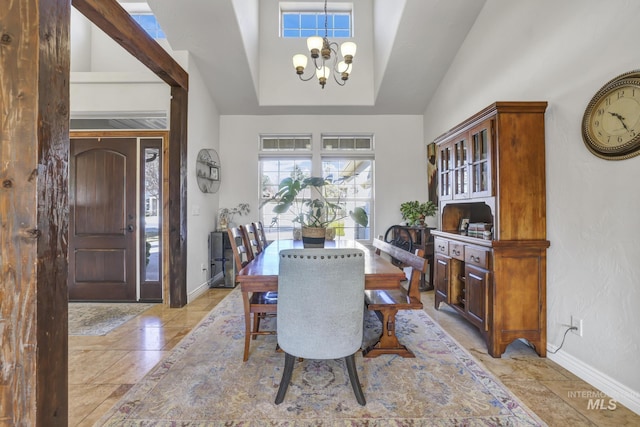 dining space featuring a chandelier, high vaulted ceiling, and baseboards