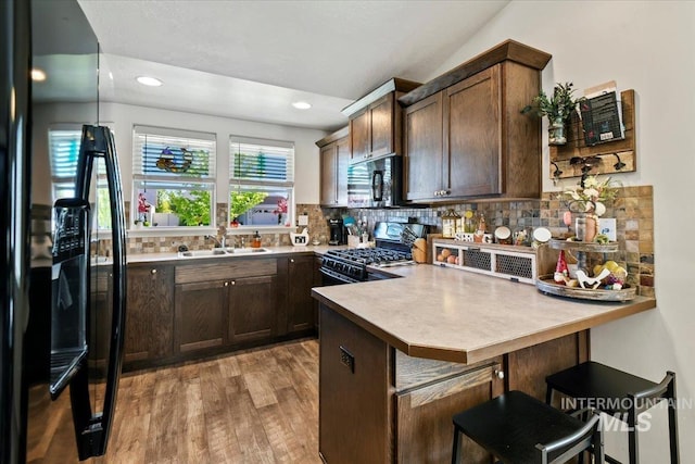 5416 Junegrass Way, Caldwell, ID 83607 - kitchen featuring black appliances, a sink, a peninsula, light wood finished floors, and dark brown cabinetry