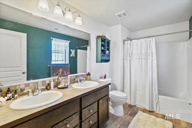 5416 Junegrass Way, Caldwell, ID 83607 - full bathroom with wood finished floors, double vanity, shower / bathtub combination with curtain, and toilet