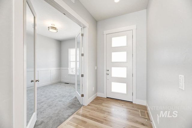 foyer entrance with baseboards, wood finished floors, and french doors