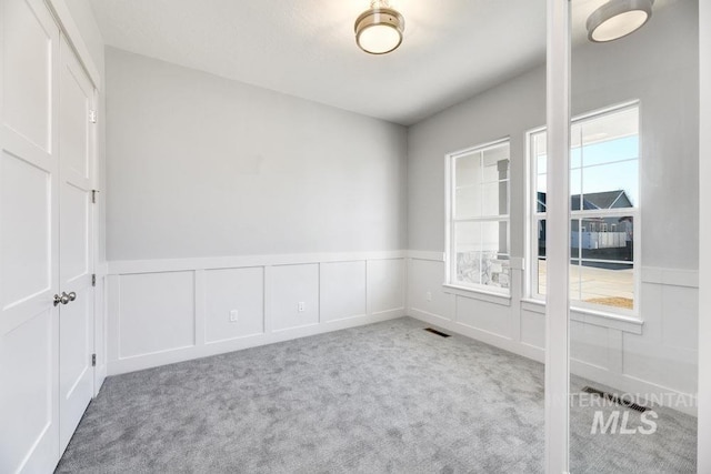 unfurnished room featuring visible vents, carpet floors, and plenty of natural light