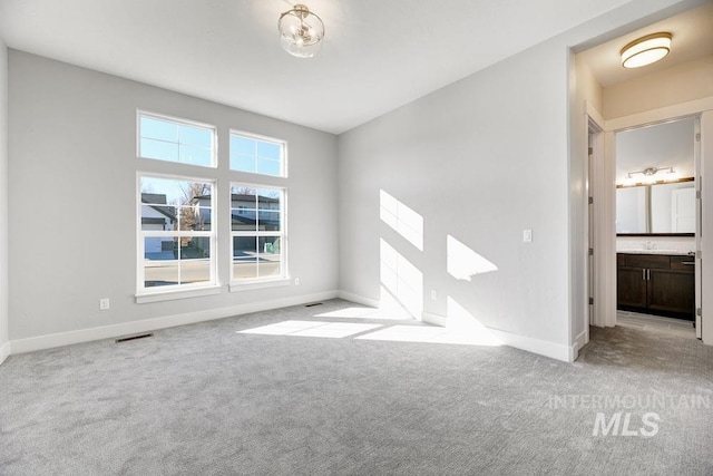 carpeted empty room with visible vents and baseboards