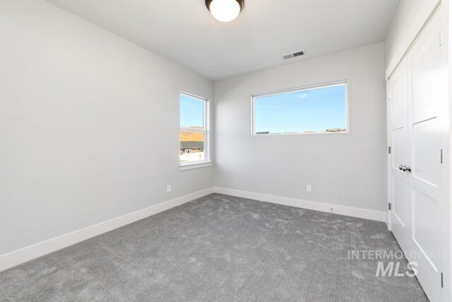 carpeted spare room featuring baseboards and visible vents