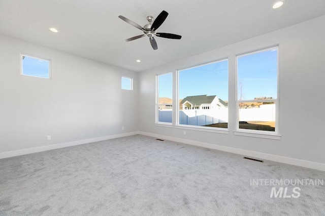 unfurnished room with a wealth of natural light, carpet floors, and baseboards