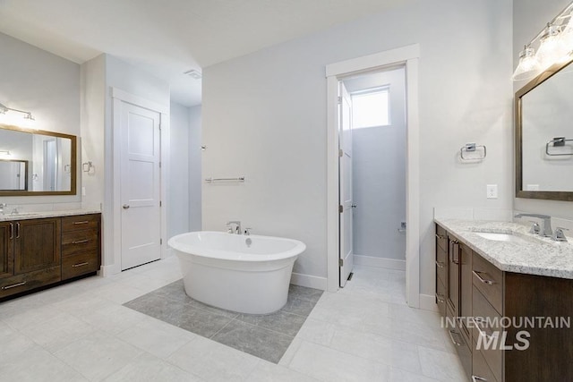 bathroom featuring two vanities, a sink, and a freestanding bath