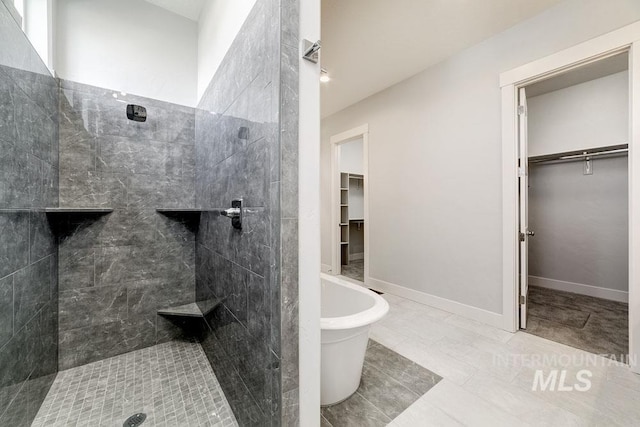 full bath with a freestanding tub, a spacious closet, and tiled shower