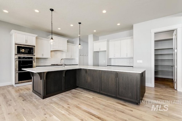 kitchen with a sink, white cabinetry, stainless steel appliances, and light countertops