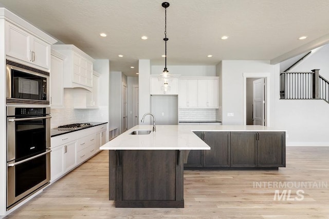 kitchen featuring light wood-style flooring, a sink, appliances with stainless steel finishes, and a large island