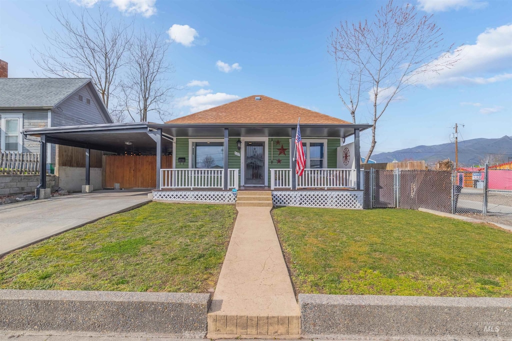 bungalow-style house with fence, a front lawn, a porch, and a carport