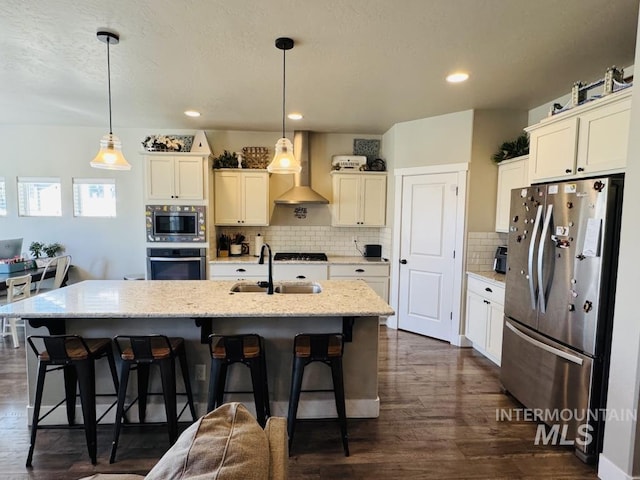 805 Drayton Ave, Twin Falls, ID 83301 - kitchen featuring stainless steel appliances, a sink, wall chimney range hood, a breakfast bar area, and tasteful backsplash