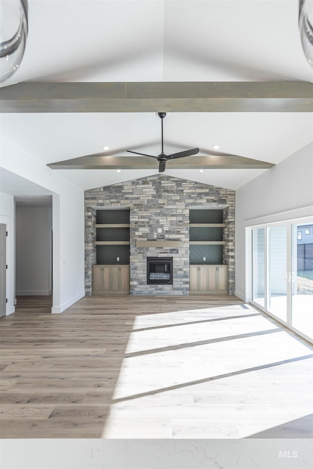 unfurnished living room with vaulted ceiling with beams, hardwood / wood-style flooring, a stone fireplace, and ceiling fan