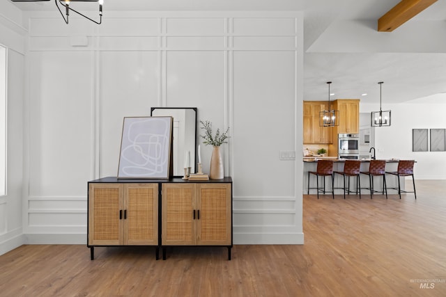 room details with double oven, sink, an inviting chandelier, and hardwood / wood-style flooring