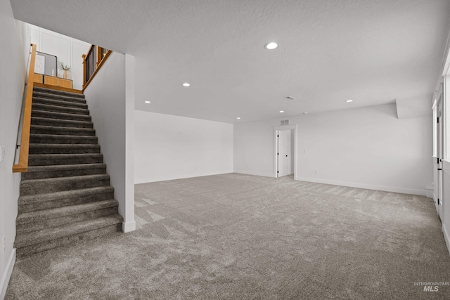 unfurnished living room with carpet flooring and a textured ceiling