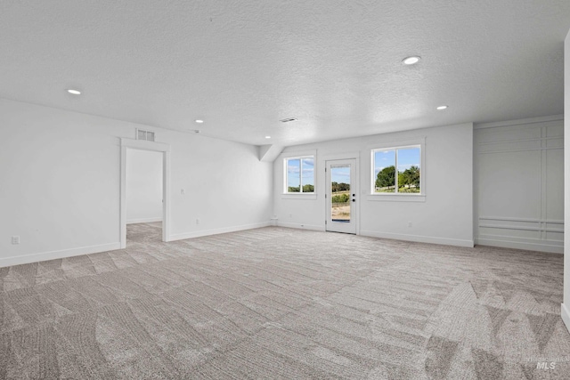 empty room featuring a textured ceiling and light colored carpet