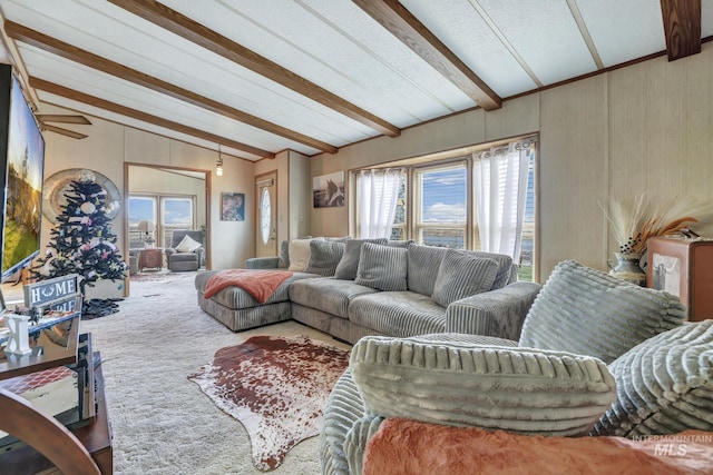 carpeted living room with plenty of natural light and lofted ceiling with beams