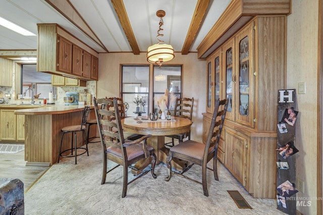 dining area with beamed ceiling and sink