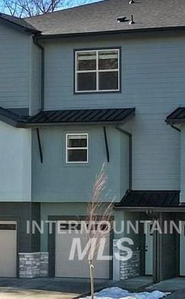 view of side of property featuring metal roof, a standing seam roof, and a garage