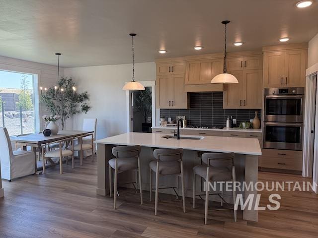 4624 N Alameda Creek Ave, Meridian, ID 83646 - kitchen with stainless steel double oven, tasteful backsplash, light countertops, an island with sink, and a kitchen bar