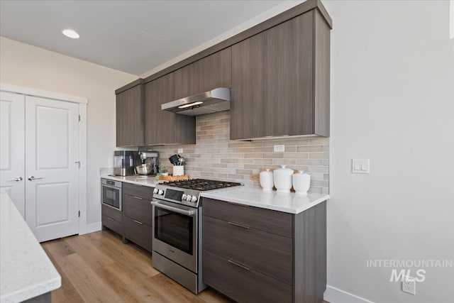 18245 N Arch Haven Way, Nampa, ID 83687 - kitchen featuring stainless steel appliances, under cabinet range hood, baseboards, and decorative backsplash
