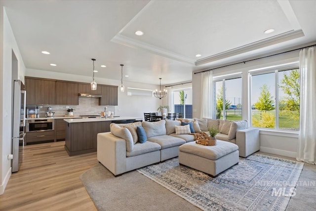 18245 N Arch Haven Way, Nampa, ID 83687 - living room featuring a raised ceiling, recessed lighting, light wood-type flooring, a chandelier, and baseboards