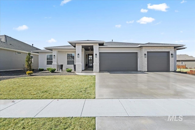 prairie-style house with a garage, stucco siding, driveway, and a front yard