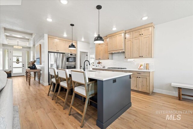 kitchen with decorative backsplash, light wood-style flooring, light countertops, light brown cabinets, and a sink