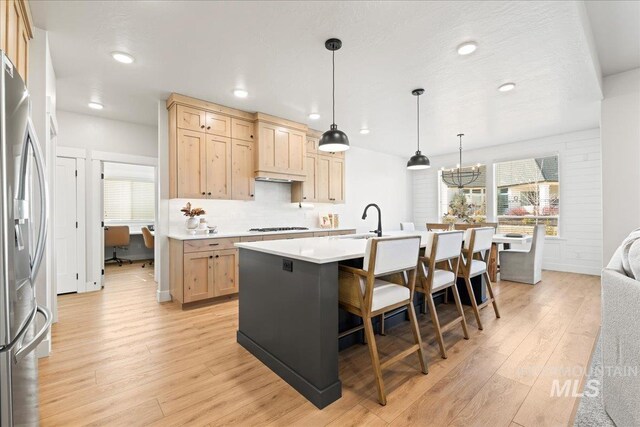 kitchen with gas stovetop, light wood finished floors, light brown cabinets, a sink, and stainless steel fridge with ice dispenser