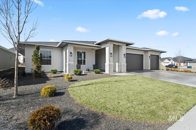 prairie-style house featuring an attached garage, a front yard, concrete driveway, and stucco siding