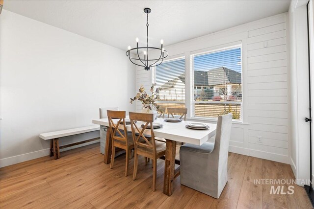 dining room featuring light wood-style floors, a chandelier, and baseboards