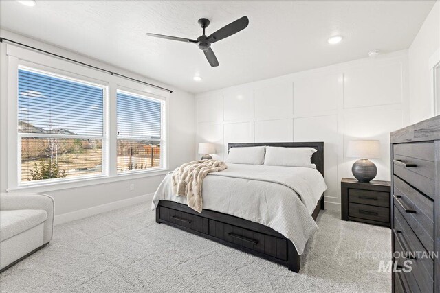 carpeted bedroom with baseboards, ceiling fan, and a decorative wall