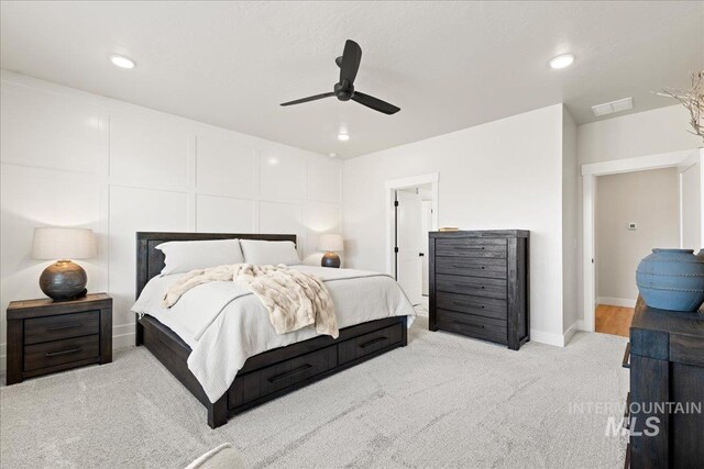 carpeted bedroom with ceiling fan, recessed lighting, a decorative wall, visible vents, and baseboards