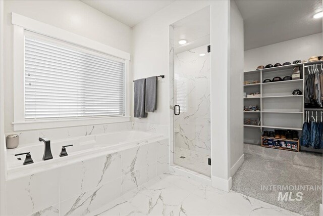 bathroom with marble finish floor, a marble finish shower, a walk in closet, and a bath