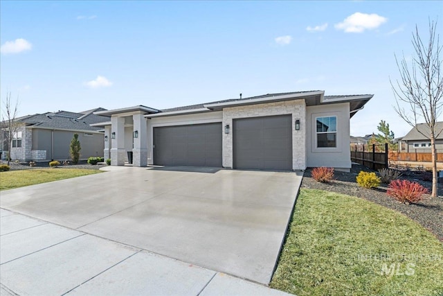 prairie-style home with a garage, driveway, a front yard, and fence